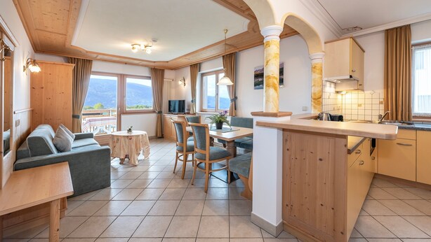 Une cuisine moderne avec des meubles en bois, un coin repas comprenant une table et des chaises, et un canapé.