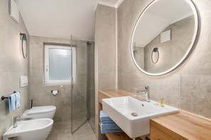A modern bathroom with a glass-enclosed shower, a toilet, a sink with a wooden countertop, and a large mirror. - 'Residence Diana Apartment 303' with Mountain View, Balcony & Wi-Fi (Terenten)
