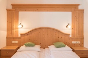 Un lit double avec deux oreillers, une tête de lit en bois, des lampes de chevet et une table de chevet avec un tiroir.