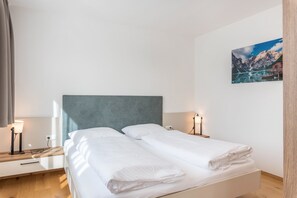 Un lit double avec une tête de lit, des lampes de chevet, une petite table et un tableau au mur.