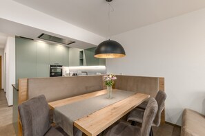 A modern dining area with a wooden table, grey upholstered chairs, and a black pendant light. - 'Residence Diana Apartment 401' with Mountain View & Wi-Fi (Terenten)