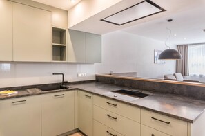 Une cuisine moderne dotée d’un évier encastré, d’une grande fenêtre et d’un luminaire suspendu.