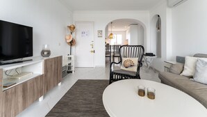 Ein modernes Wohnzimmer mit Fernseher, einem weißen Couchtisch und einer Couch.