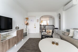 Un salon moderne avec un téléviseur à écran plat, une table basse blanche et un canapé.