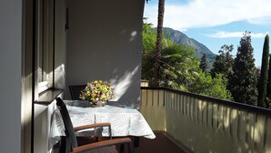 A balcony with a table, chair, and a flower vase. - Villa Coris Apartment Magnolia 110 sqm with Garden (Merano)