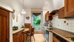 A kitchen with wooden cabinets, a dining table with chairs, a microwave, and a coffee maker. - Villa Coris Apartment Magnolia 110 sqm with Garden (Merano)