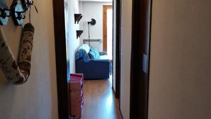 Käytävä johtaa makuuhuoneeseen, jossa on sänky, patteri ja seinällä oleva kello.