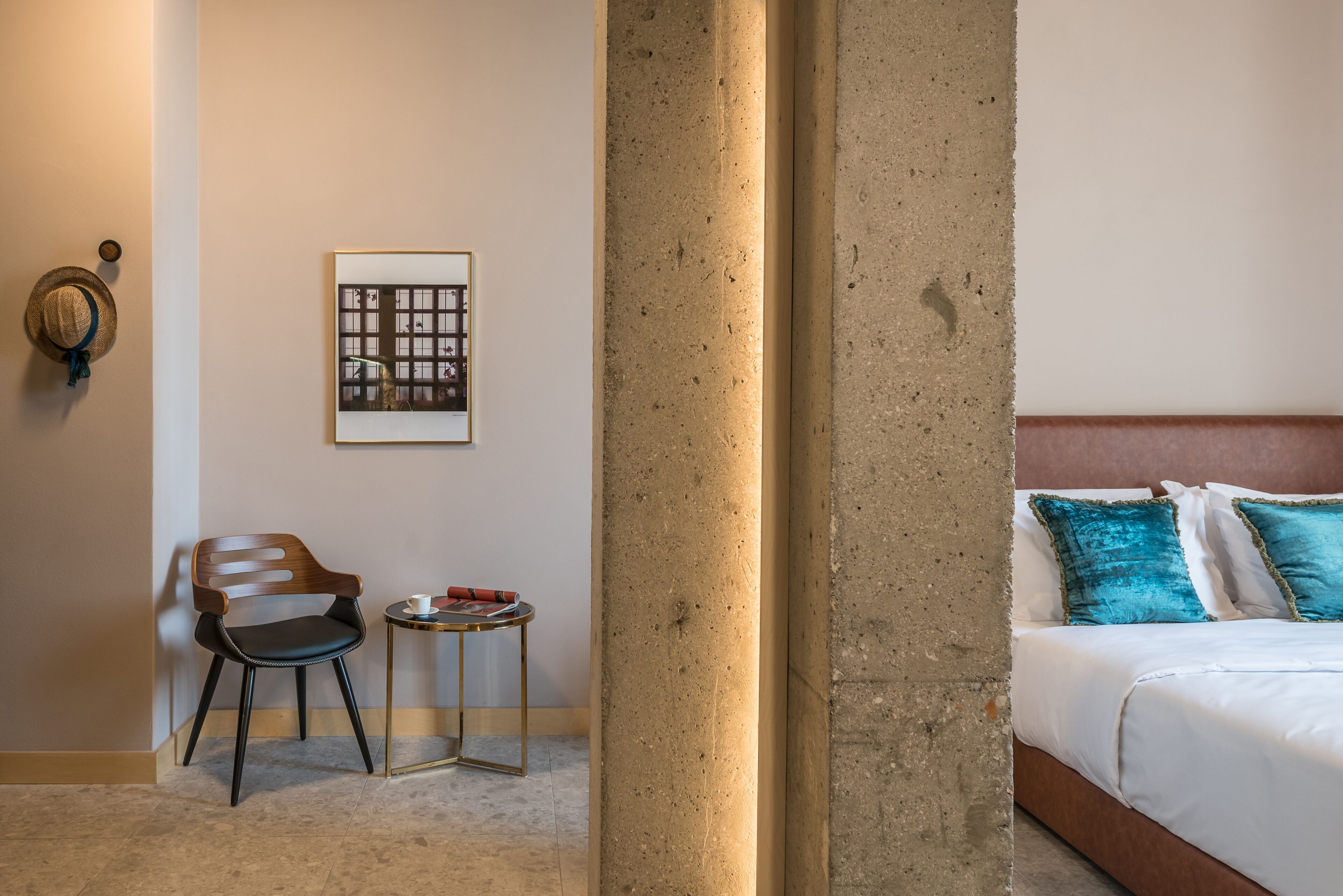 Une chambre d’hôtel avec un lit, une chaise, une petite table et un tableau encadré au mur.