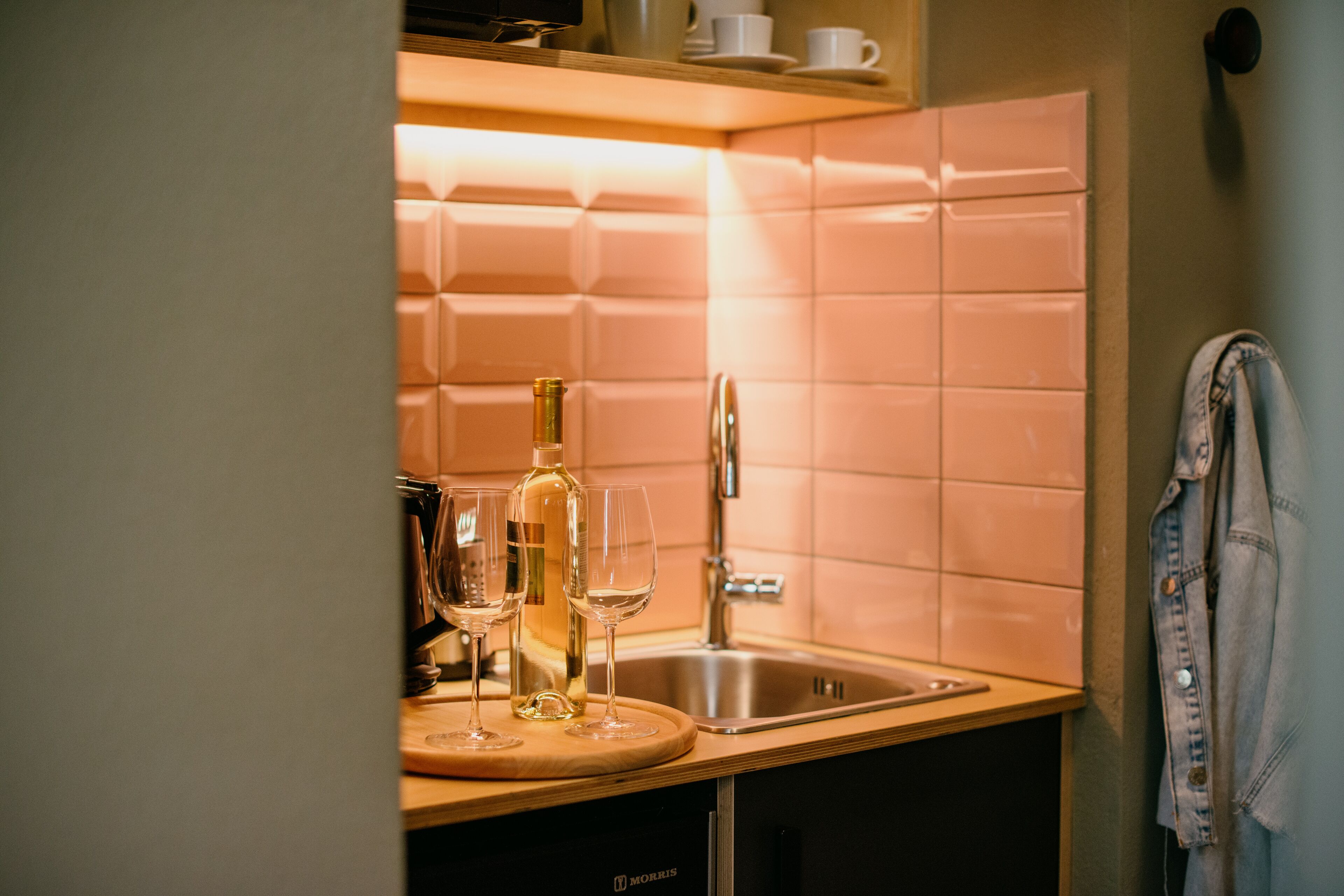 A kitchen with a sink, a countertop, and a bottle of wine.