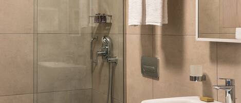 A modern bathroom with a glass-enclosed shower, a white toilet, and a sink with a mirror above it.