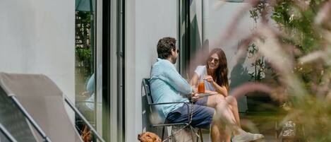 A couple sitting on a balcony with a dog.