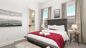 Ein modernes Hotelzimmer mit einem großen Bett, einem Nachttisch mit Lampe, einem kleinen runden Tisch und einem Gemälde an der Wand.
