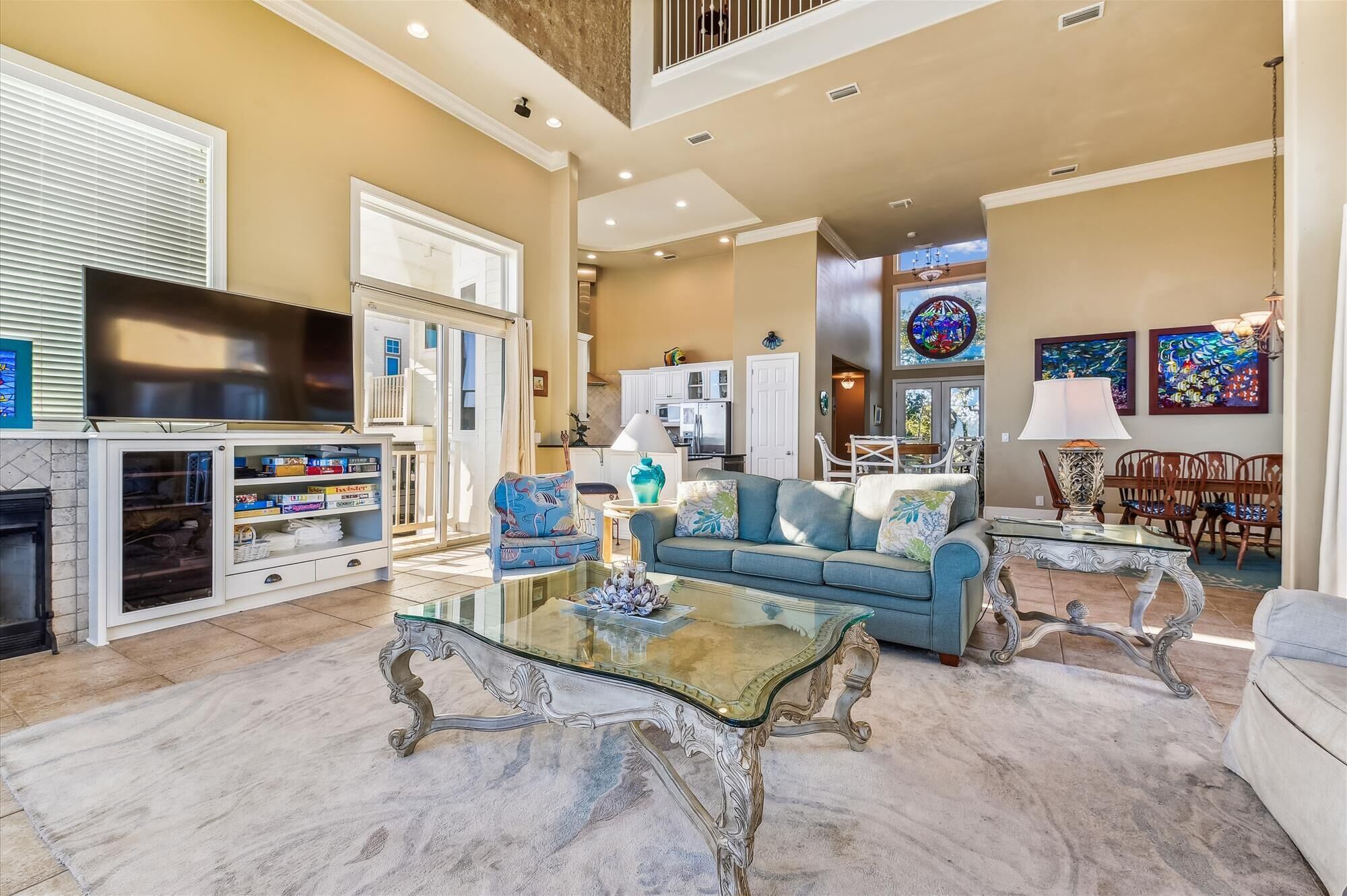 A spacious living room with a blue sofa, a glass coffee table, and a fireplace.