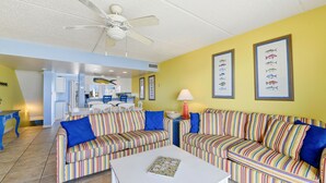 A living room with striped sofas, a white coffee table, and framed fish pictures on the wall. - Located right on the beachfront, this bright, cheerful and beautiful well-appointed Villa. (St. George Island)