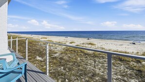 A balcony with a view of a beach and ocean. - Located right on the beachfront, this bright, cheerful and beautiful well-appointed Villa. (St. George Island)