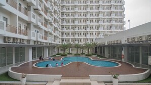 A modern apartment complex with a central swimming pool, surrounded by balconies and air conditioning units. - S&A Property 4 (Citaringgul)