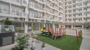 A multi-story residential building with balconies, a children's play area, and potted plants. - S&A Property 4 (Citaringgul)