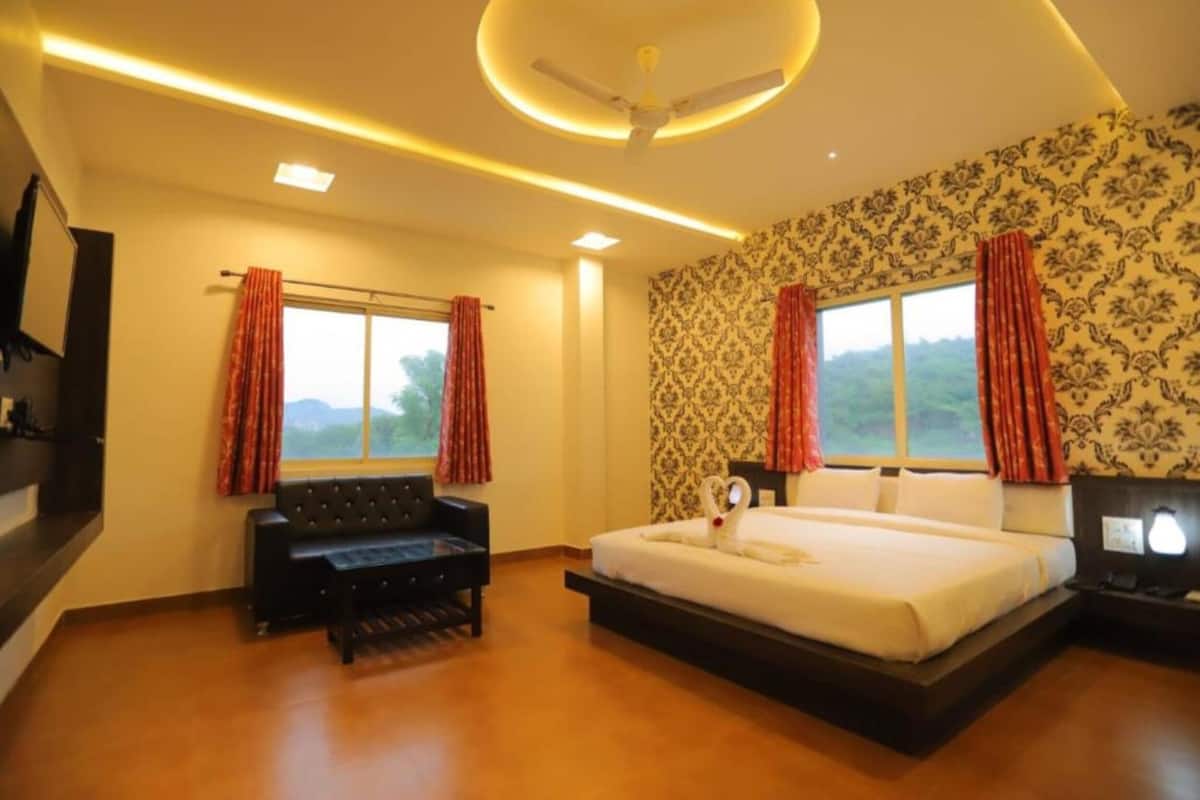 A hotel room with a large bed, a sofa, a desk, and a ceiling fan.