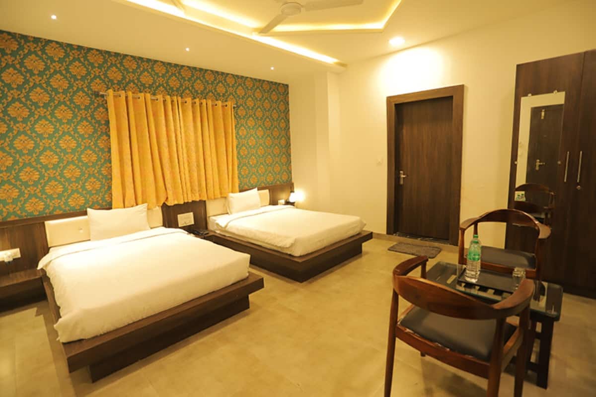 A hotel room with two beds, a wooden chair, a table with a bottle, and a wardrobe.