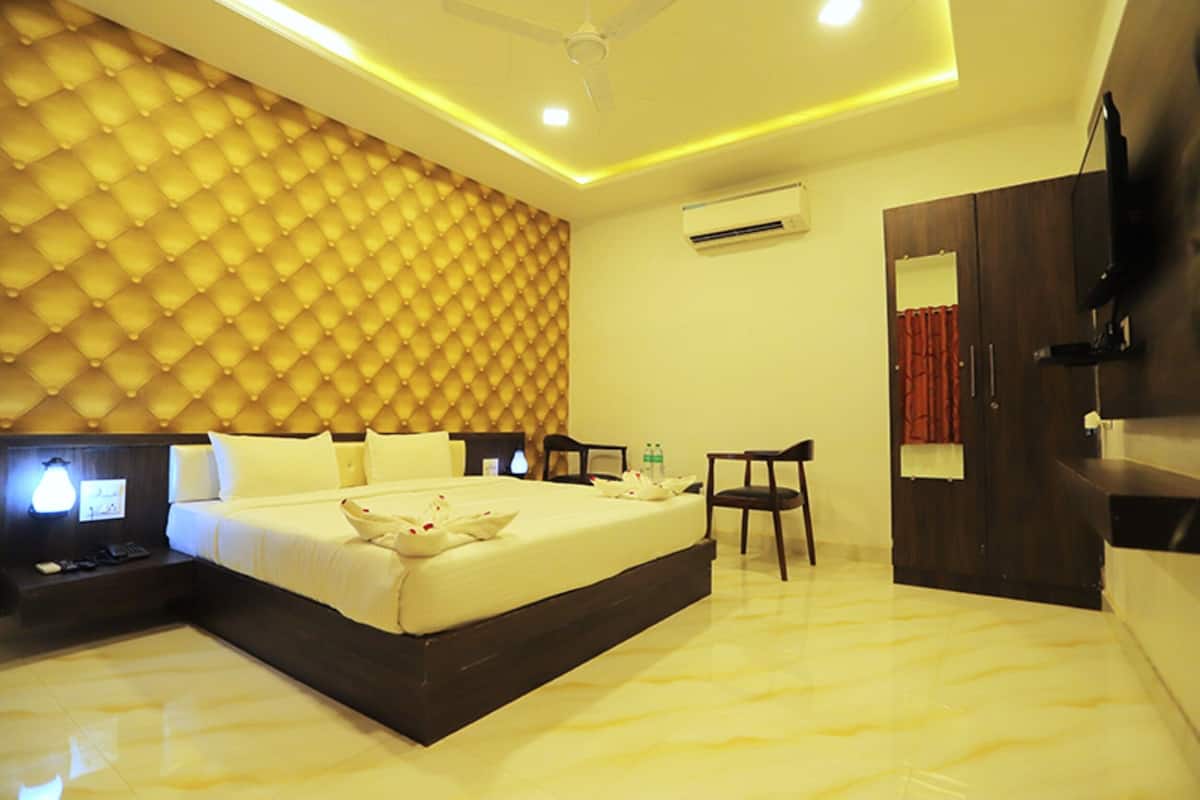 A hotel room with a large bed, a desk, a chair, a wardrobe, and a ceiling fan.