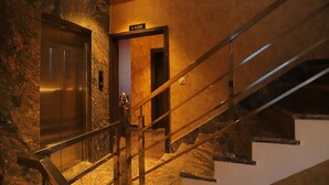 Um elevador moderno e uma escada com um sinal indicando o primeiro andar.