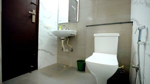 Un baño con inodoro blanco, lavamanos y ducha.