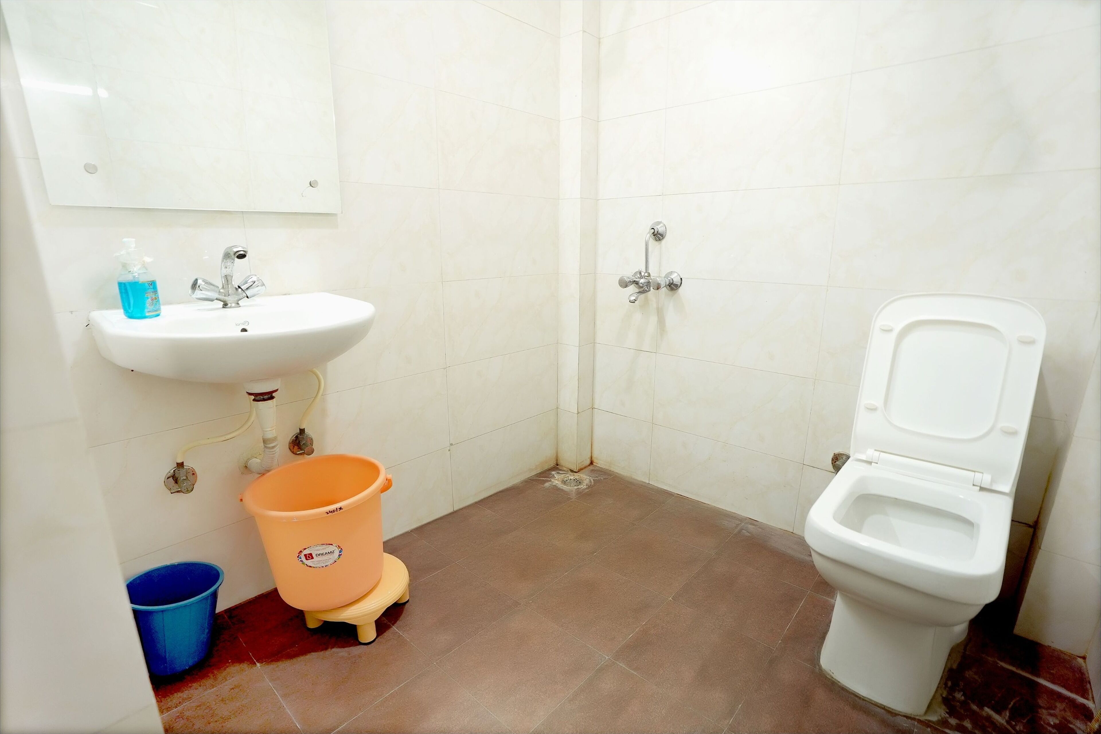 Een badkamer met een wastafel, toilet en een blauwe emmer.