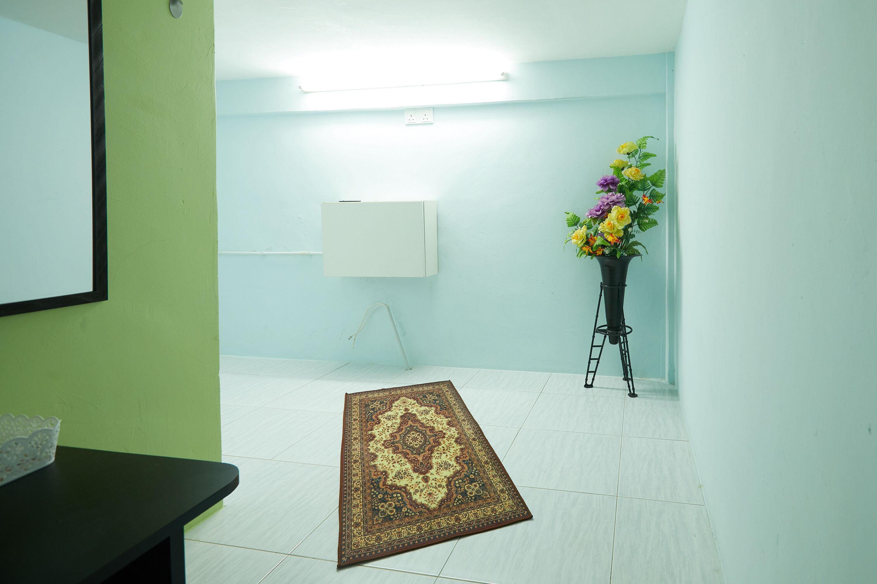 A room with a white tiled floor, a standing lamp, and a floral arrangement on a stand.