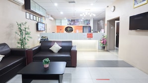 A reception area with a reception desk, a sofa, a coffee table, and a television. - Sy Jerantut Hotel (Jerantut)
