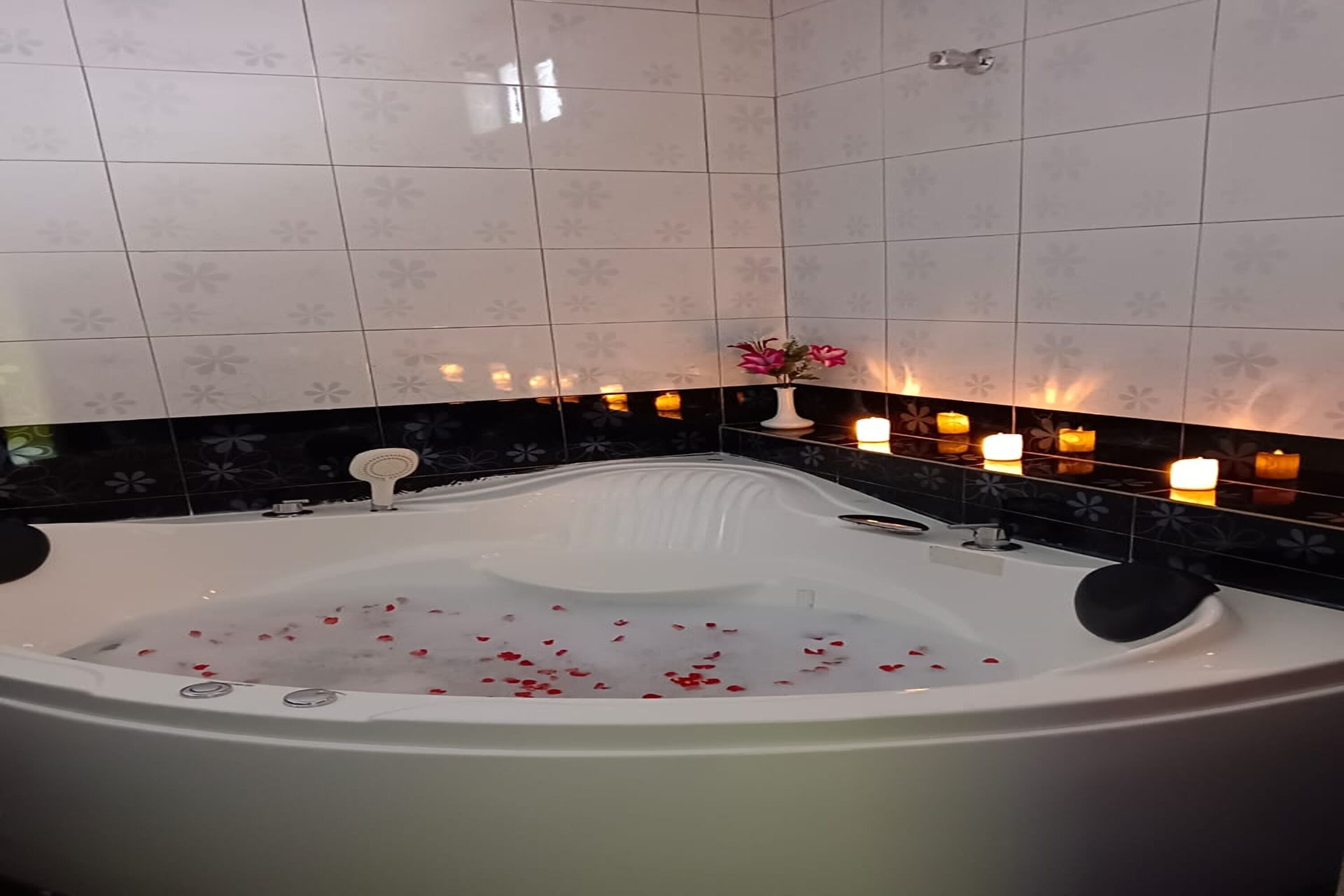 A bathroom with a large bathtub, tiled walls, and candles.