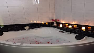 A bathroom with a large bathtub, tiled walls, and candles.