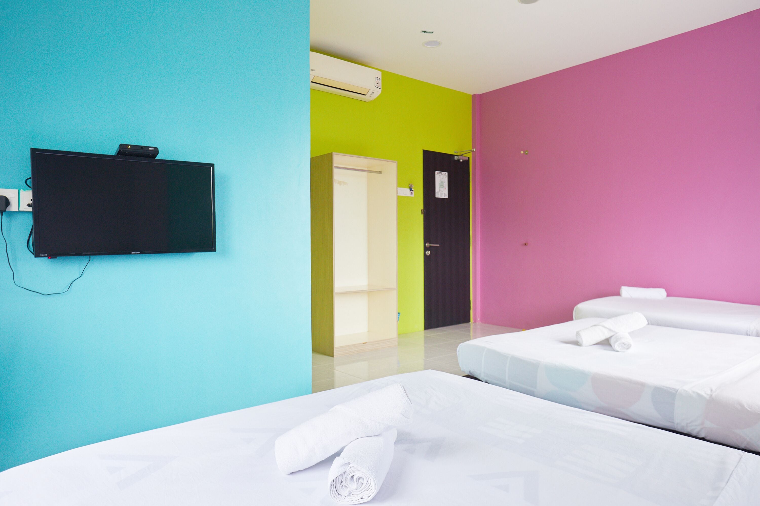 Habitación de hotel con dos camas, un televisor y una puerta que da a un baño.