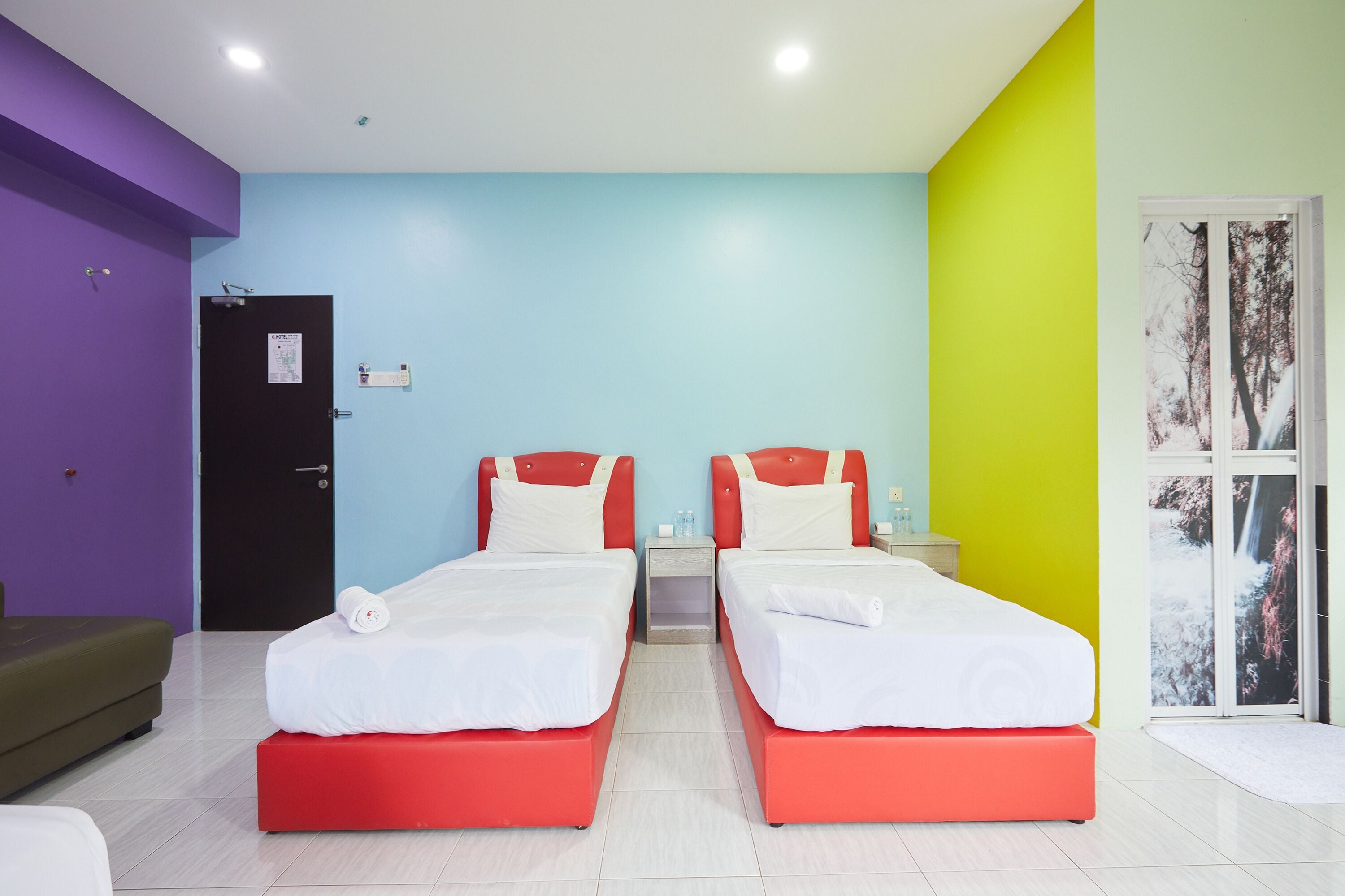 Une chambre avec deux lits, un canapé, une porte et une fenêtre donnant sur un beau paysage.