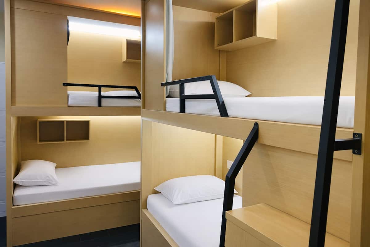 Habitación con literas, paredes de madera y una pequeña estantería.