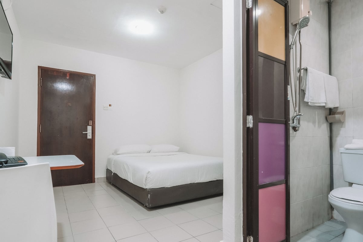 Una habitación de hotel con cama, escritorio, ducha y baño.