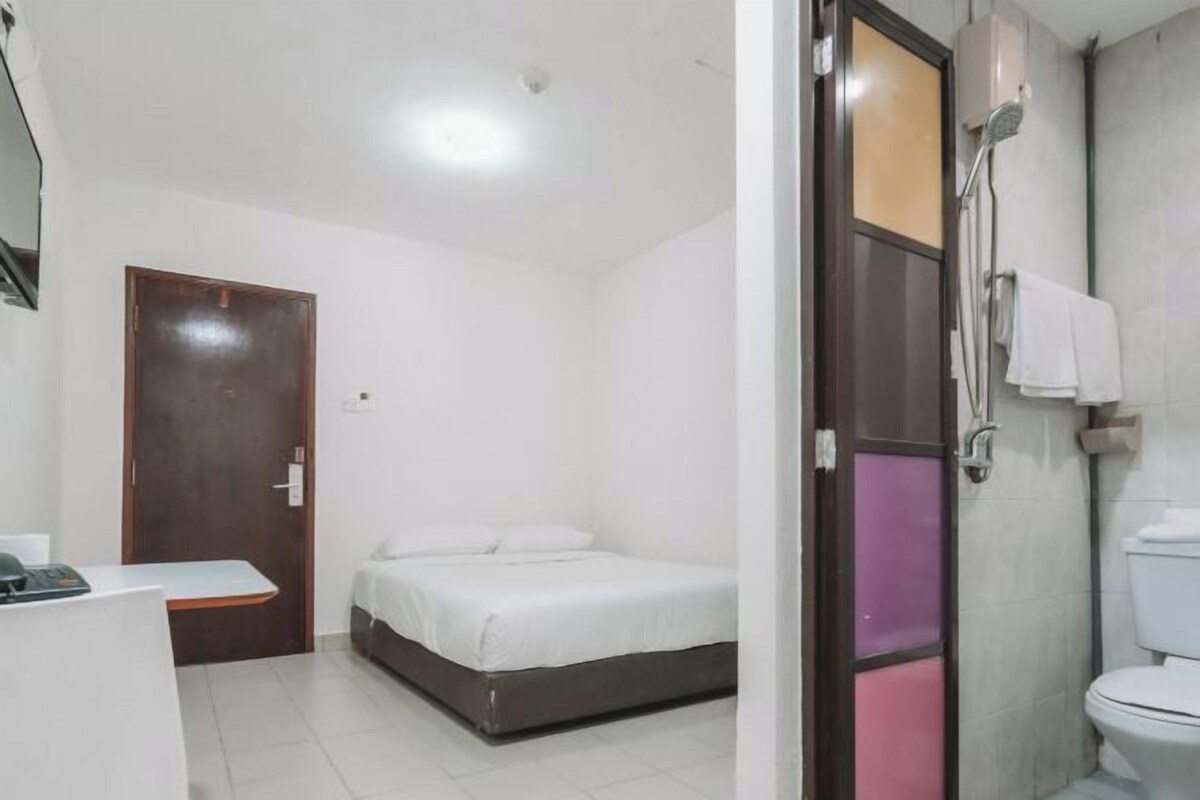 Una habitación pequeña y limpia con cama, escritorio y baño.