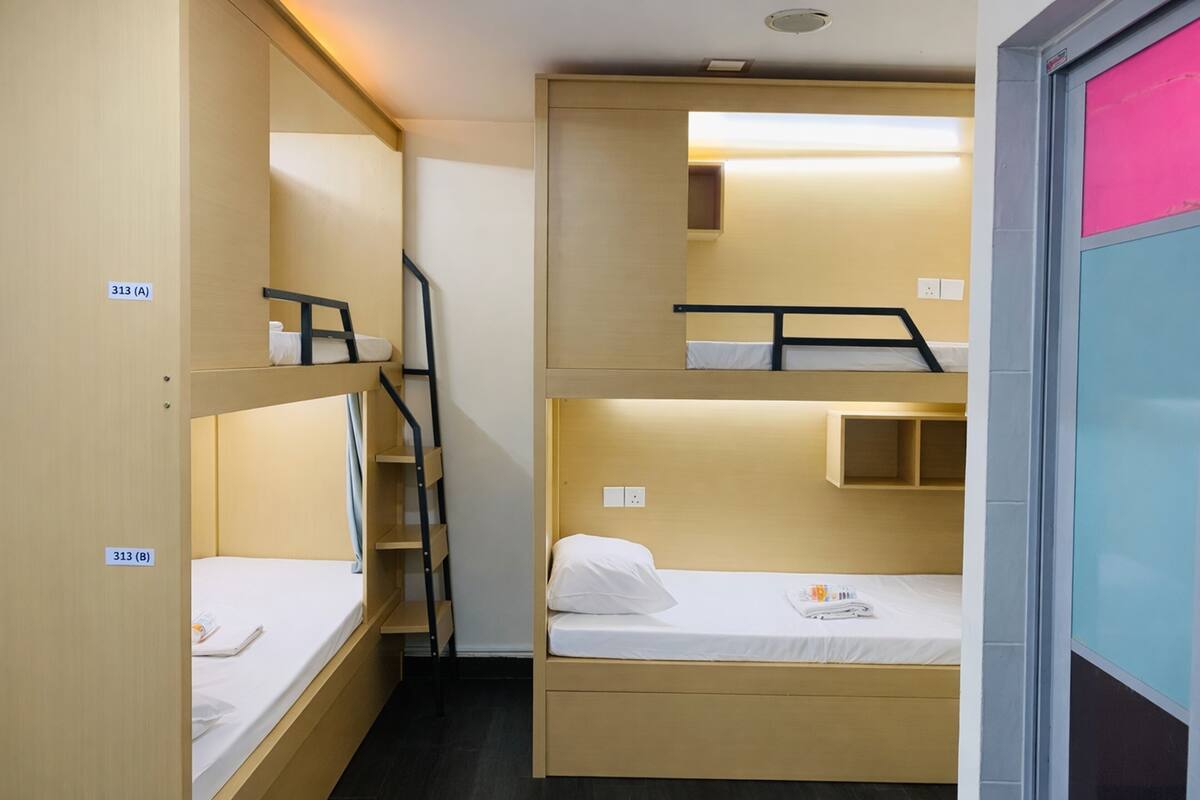 Habitación tipo dormitorio con literas, una escalera y un estante pequeño.