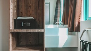 A bathroom with a wooden shelf, a black radio, a white sink, a mirror, and a trash can. - A Hotel Desker (Singapore)