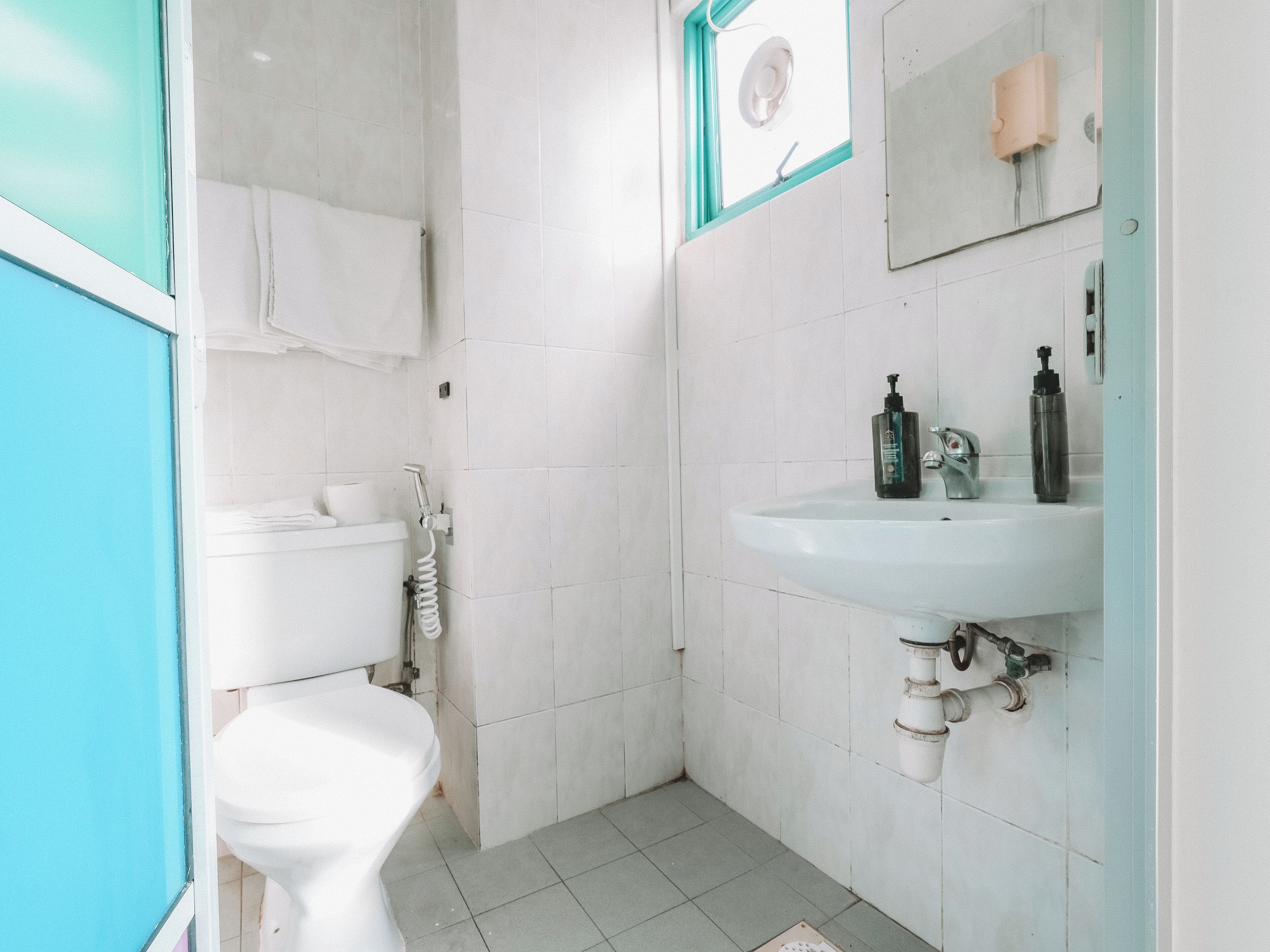 Un baño pequeño y limpio, con inodoro, lavamanos y ventana.