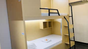 Una cama litera con un estante debajo de la cama superior y una escalera a un lado.