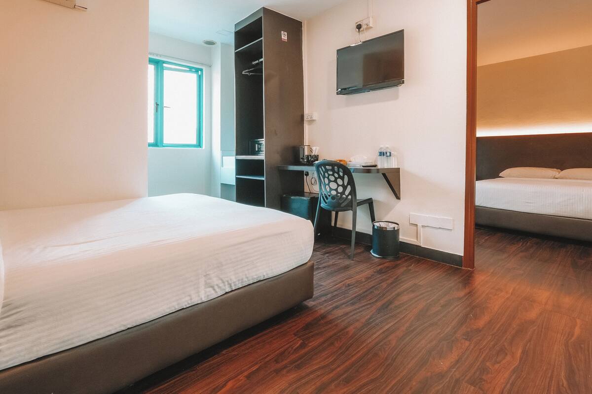 Una habitación de hotel con cama, escritorio, silla, televisor y armario.