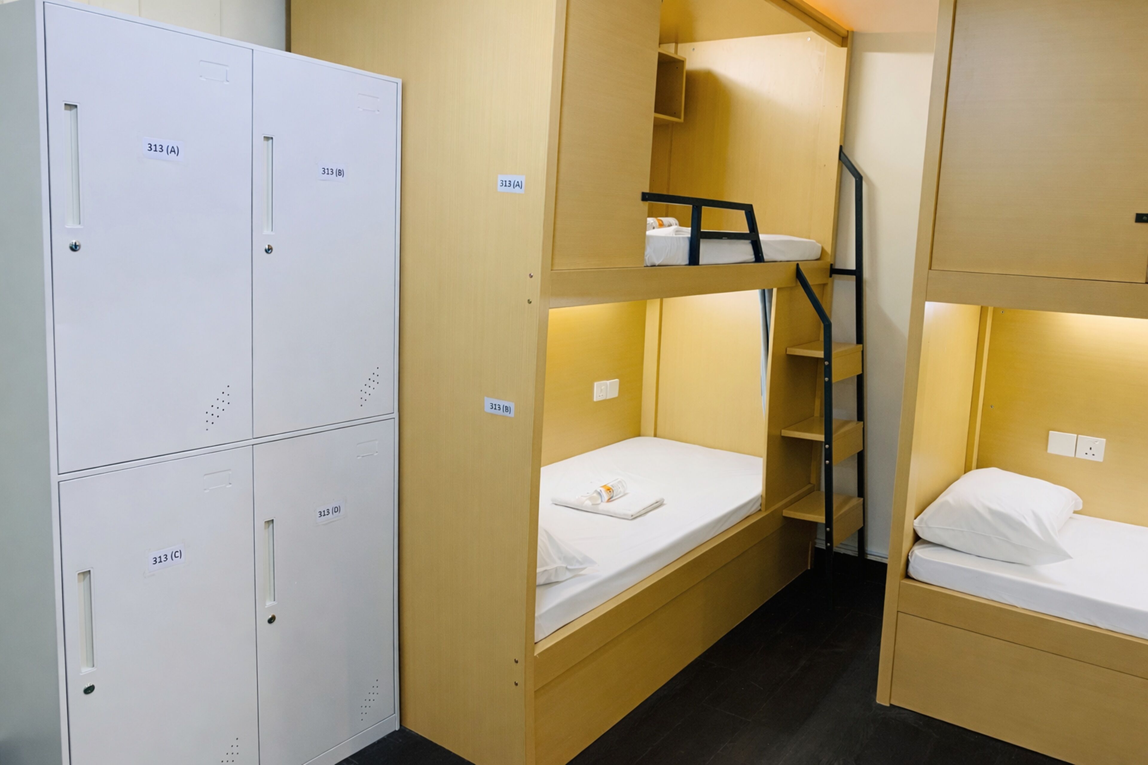 A dormitory room with bunk beds, a wardrobe, and a small desk.