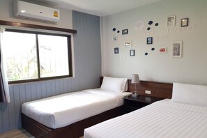 Ein Hotelzimmer mit zwei Einzelbetten, einem Fenster und einer Wand mit gerahmten Bildern und einer Uhr.