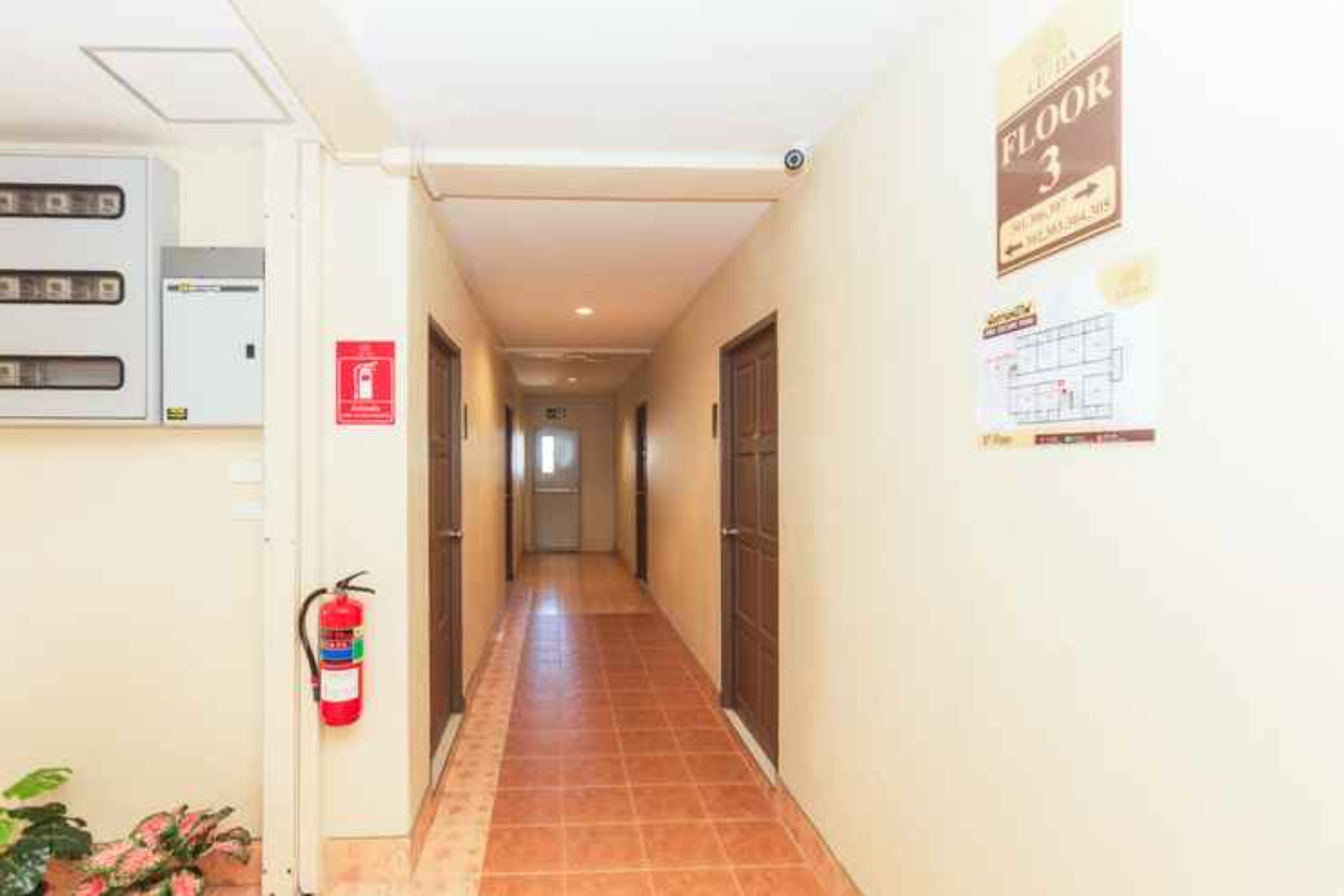 Un pasillo con un extintor, un cartel que indica el piso 3 y una señal de salida de incendios.