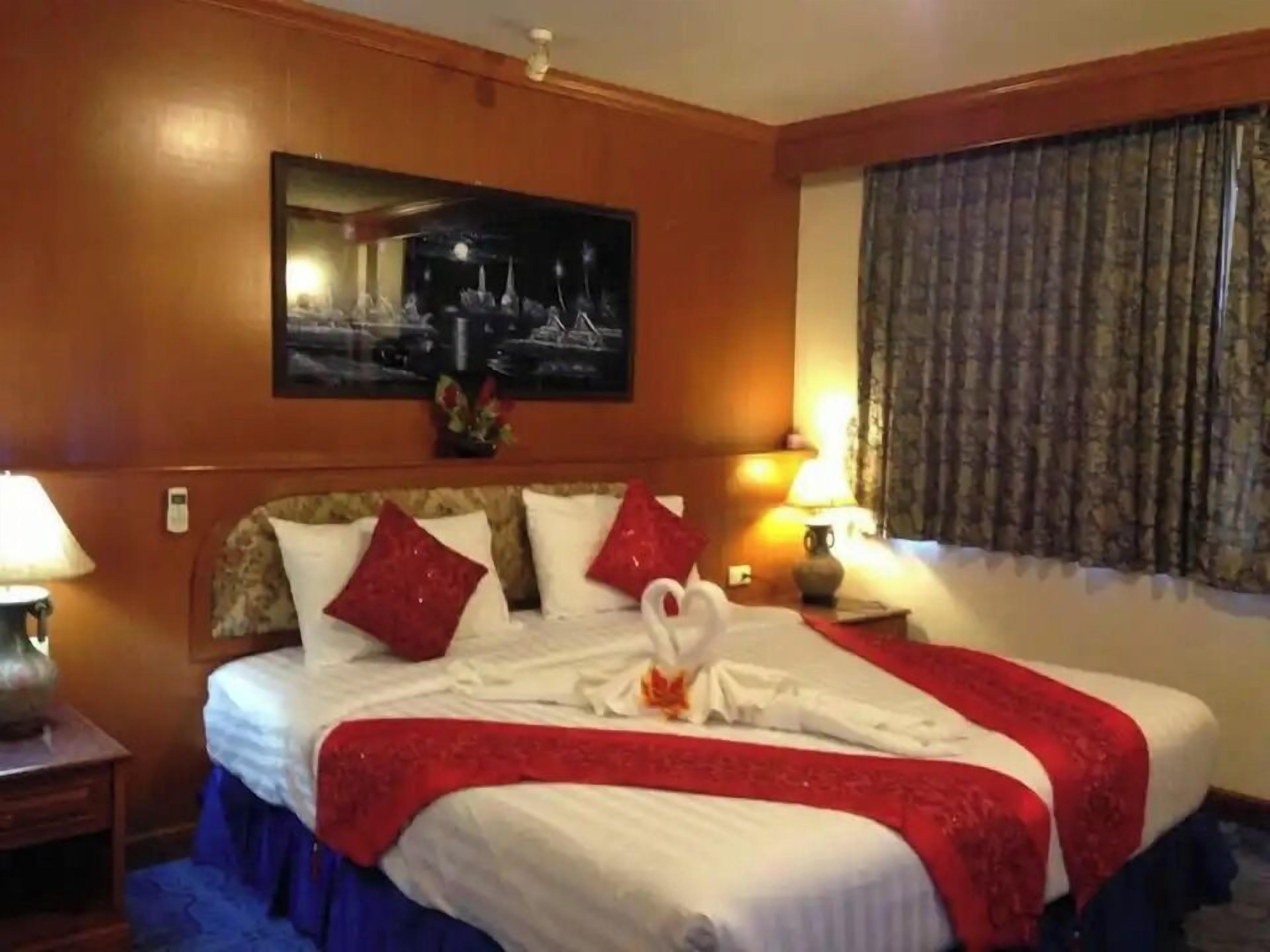 A hotel room with a bed, two bedside lamps, a painting on the wall, and a window with curtains.