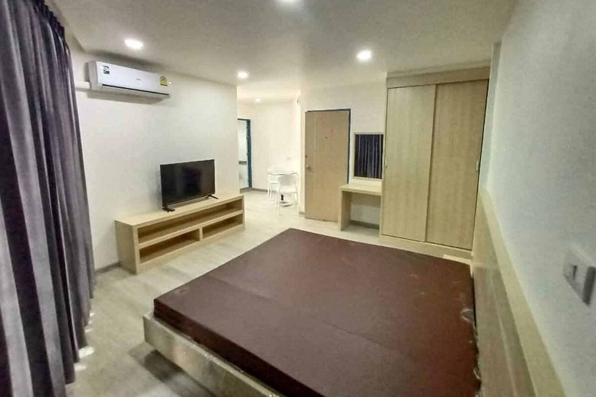 A modern bedroom with a flat-screen TV, a wardrobe, a desk, and a bed.