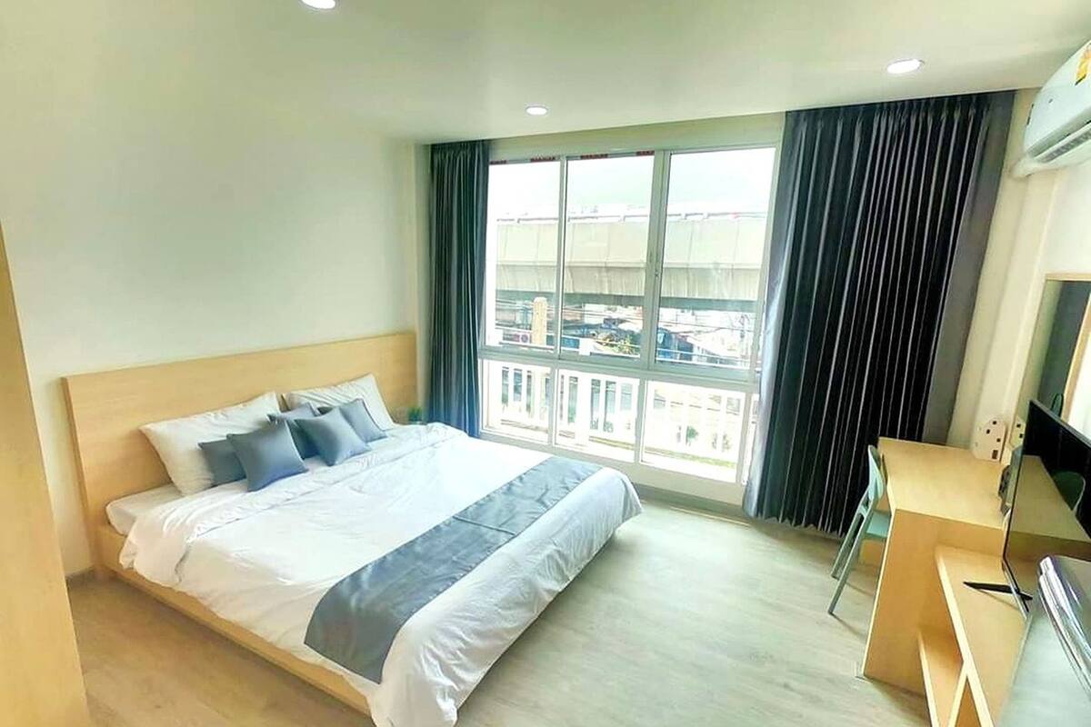 A hotel room with a large bed, a desk, and a window with curtains.