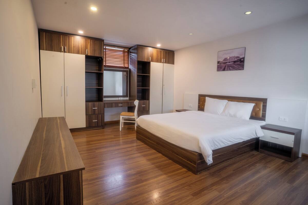 Une chambre avec un grand lit, une armoire en bois et un espace bureau.