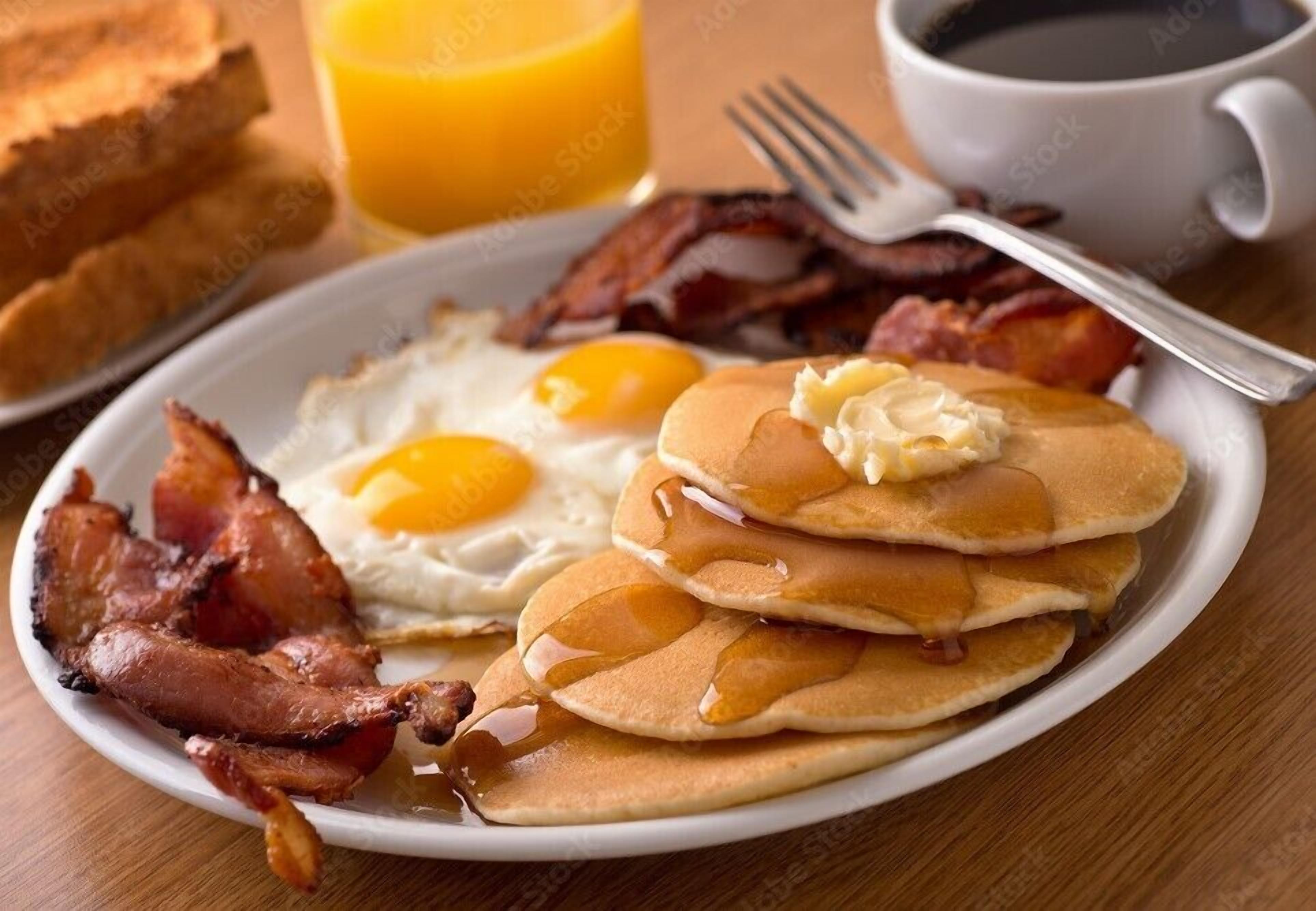 Um prato com panquecas, ovos e bacon.