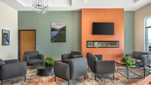 A modern lounge area with sofas, a fireplace, and artwork on the walls. - Radisson Hotel Pendleton Airport (Pendleton)